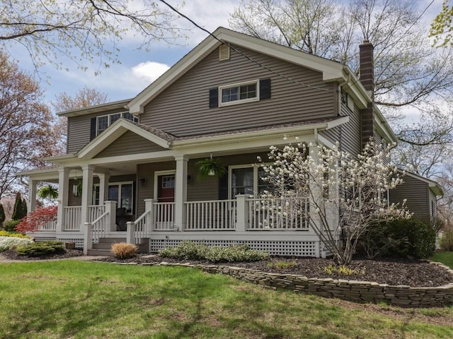 view of front facade featuring a porch, a front yard, and a chimney