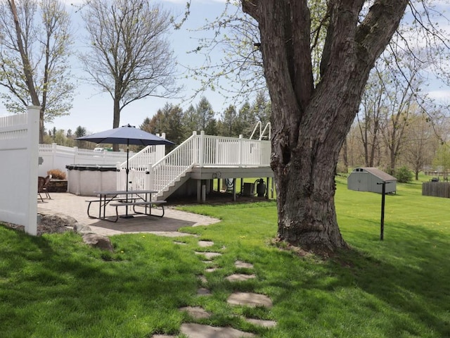 view of yard with fence, a deck, stairs, a patio area, and a hot tub
