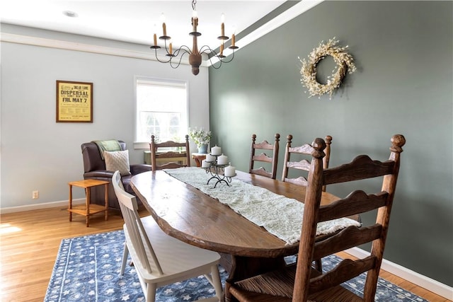 dining space featuring light wood-style floors, baseboards, and a notable chandelier