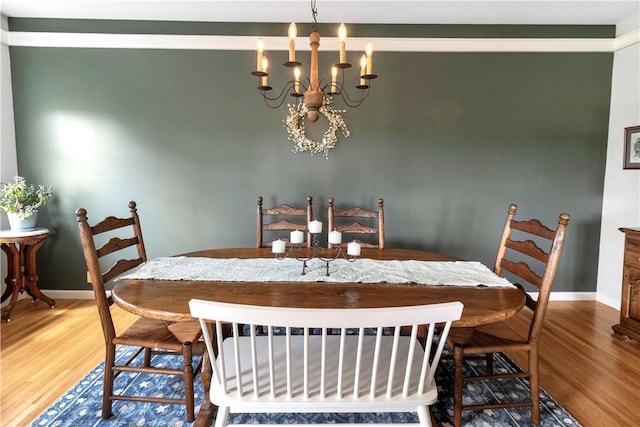 dining area with baseboards, wood finished floors, and a notable chandelier
