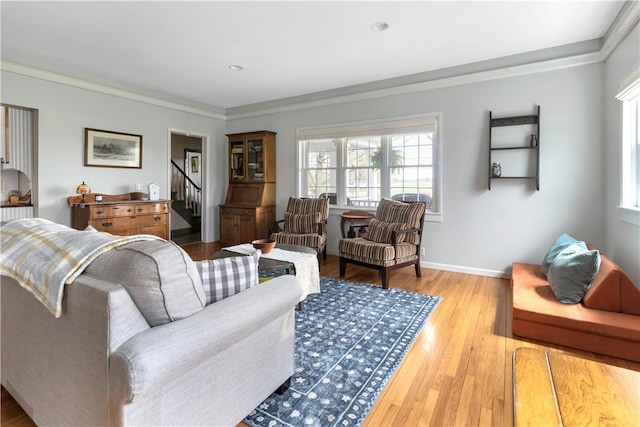 living area with crown molding, light wood-style floors, and plenty of natural light