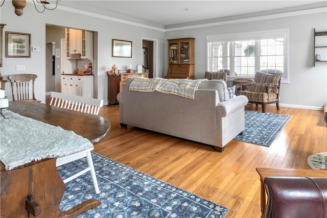 living room with light wood-type flooring, baseboards, and crown molding