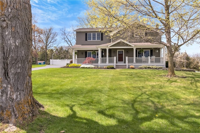 view of front of property featuring covered porch, fence, and a front yard