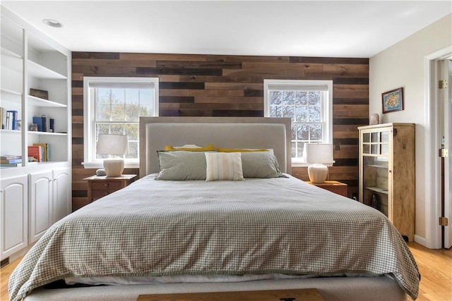 bedroom with wooden walls and light wood-type flooring