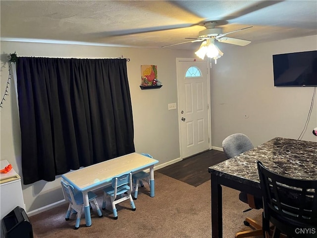 carpeted office space featuring ceiling fan and baseboards
