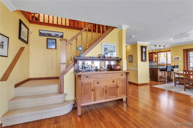 stairway with baseboards, ornamental molding, and wood finished floors