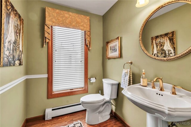 bathroom featuring wood finished floors, toilet, baseboards, a baseboard heating unit, and a sink