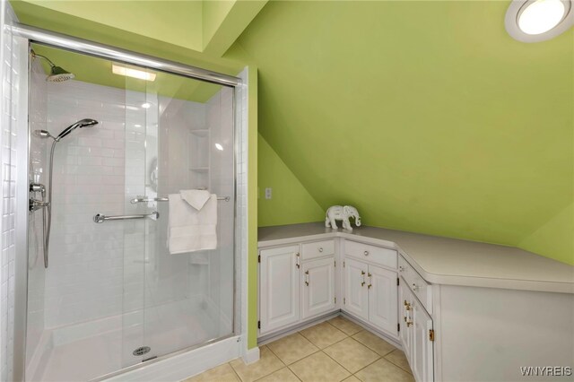 full bath with tile patterned floors, a shower stall, and lofted ceiling