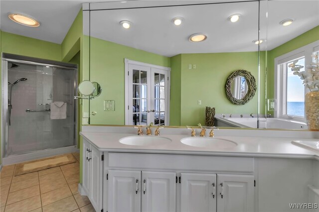 full bathroom featuring a sink, tile patterned floors, a stall shower, and double vanity