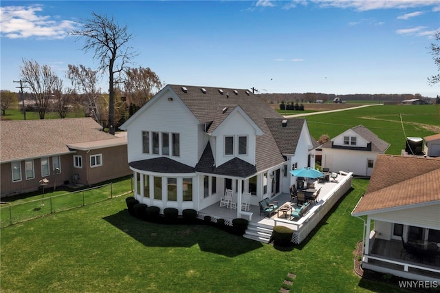 rear view of house with a lawn, a sunroom, a fenced backyard, and roof with shingles
