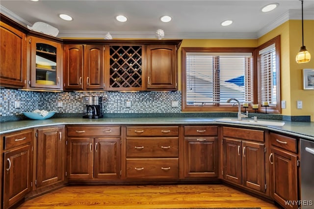 kitchen with decorative backsplash, pendant lighting, a sink, light wood-style floors, and ornamental molding