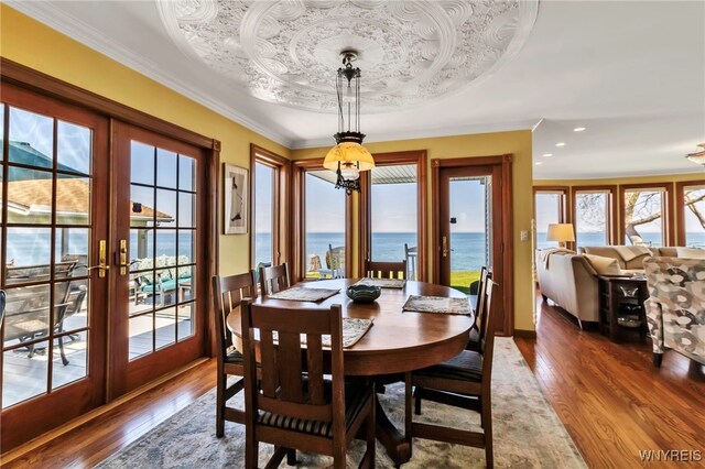 dining room with ornamental molding, dark wood-style flooring, recessed lighting, a water view, and french doors