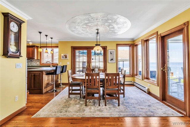 dining room featuring crown molding, baseboards, and wood finished floors
