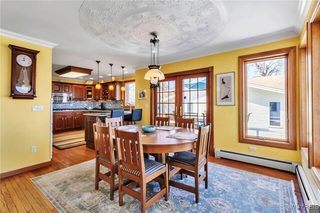 dining space with baseboards, wood finished floors, baseboard heating, and french doors