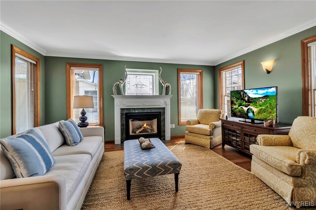 living room with crown molding, a high end fireplace, baseboards, and wood finished floors
