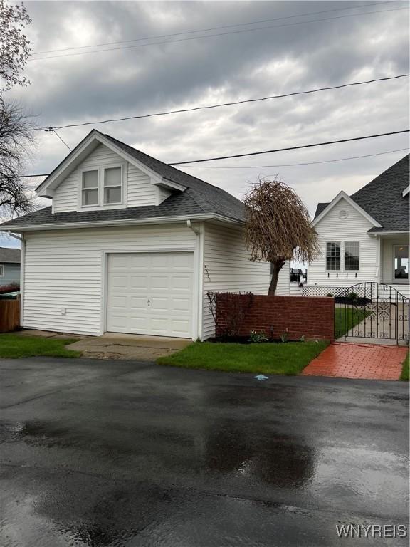 view of front facade with a garage, fence, a shingled roof, and aphalt driveway