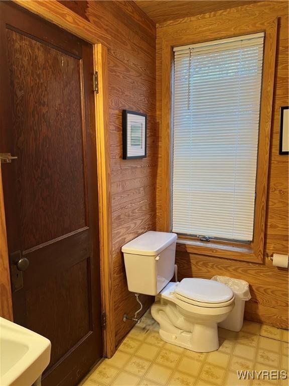 bathroom with wood walls, tile patterned floors, and toilet
