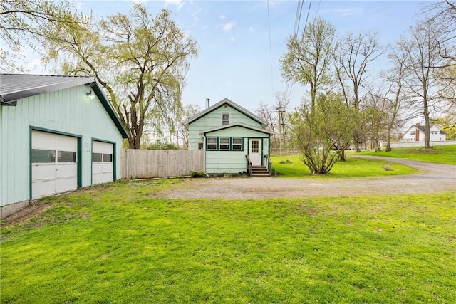 view of yard featuring fence, driveway, a detached garage, and entry steps
