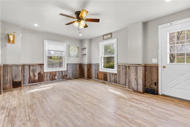 spare room featuring wooden walls, ceiling fan, wood finished floors, and a wainscoted wall