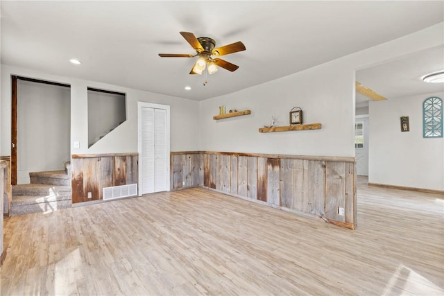 interior space with a ceiling fan, visible vents, wainscoting, and wood finished floors