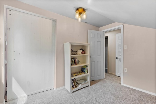 carpeted bedroom with baseboards, lofted ceiling, and a closet