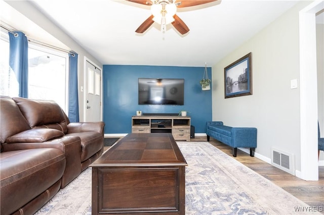 living room with a ceiling fan, baseboards, visible vents, and wood finished floors