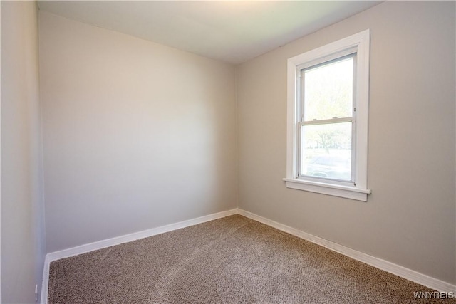 carpeted spare room featuring baseboards and plenty of natural light