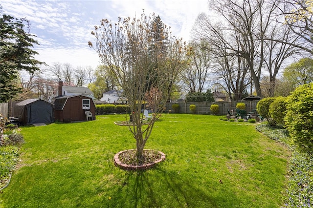 view of yard featuring a storage shed, fence, and an outbuilding