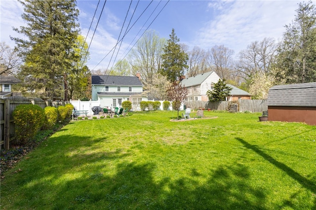 view of yard with an outbuilding, a fenced backyard, and a shed