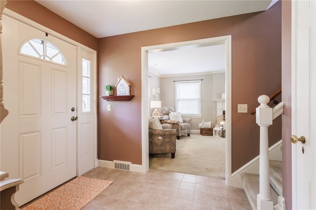 foyer featuring light carpet, stairs, baseboards, light tile patterned floors, and visible vents
