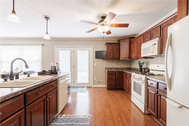 kitchen with visible vents, hanging light fixtures, a sink, white appliances, and light wood-style flooring