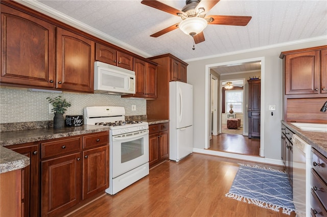 kitchen featuring wood finished floors, white appliances, ceiling fan, tasteful backsplash, and a sink