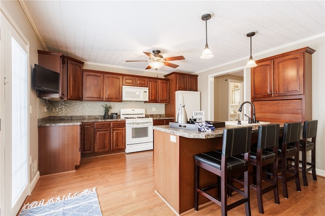 kitchen featuring ornamental molding, white appliances, a kitchen bar, a ceiling fan, and light wood-style flooring