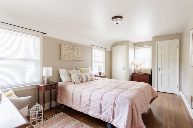 bedroom featuring baseboards, lofted ceiling, and wood finished floors