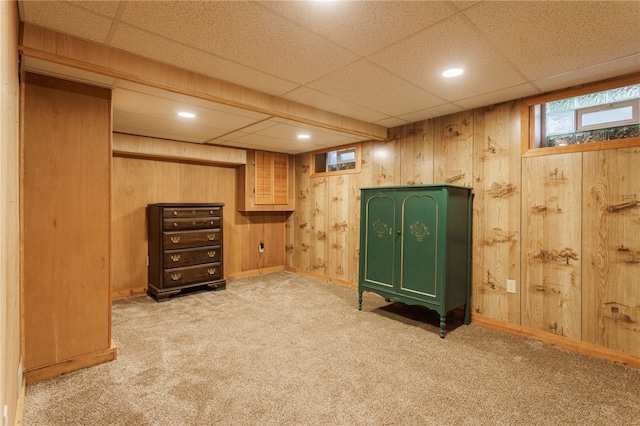 interior space featuring carpet floors, wooden walls, baseboards, and a paneled ceiling