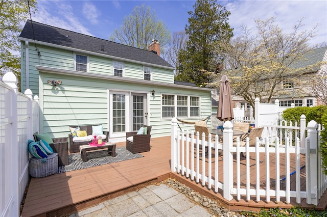 back of property featuring fence, a wooden deck, a chimney, and an outdoor living space