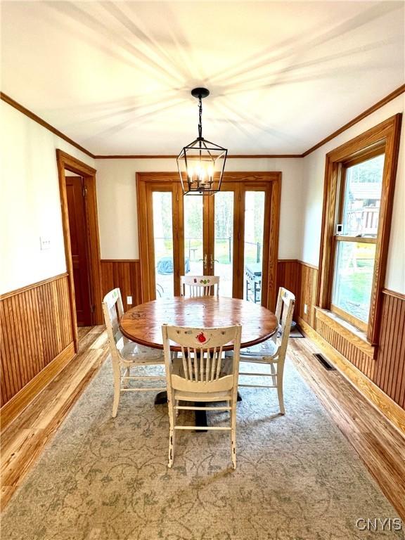 1058 State Route 48, Granby, NY 13069 - dining space featuring light wood-style floors, wood walls, a wainscoted wall, and visible vents