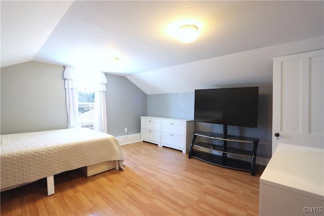 bedroom with baseboards, lofted ceiling, and light wood finished floors