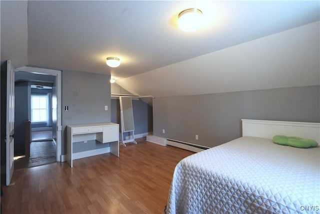 bedroom featuring baseboards, a baseboard heating unit, wood finished floors, and lofted ceiling