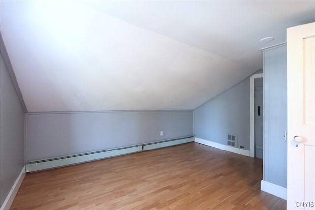 additional living space with baseboards, light wood finished floors, baseboard heating, and lofted ceiling