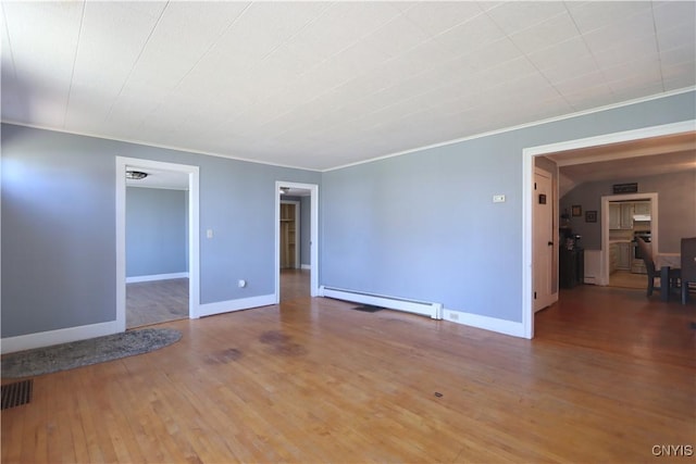 unfurnished room featuring crown molding, visible vents, wood finished floors, baseboards, and a baseboard heating unit