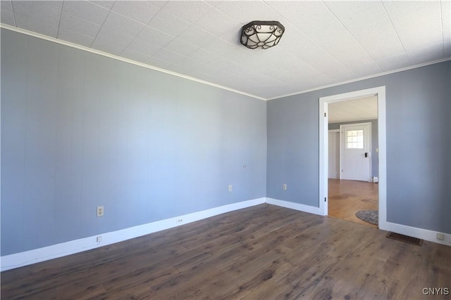 empty room featuring baseboards, ornamental molding, dark wood-style flooring, and visible vents