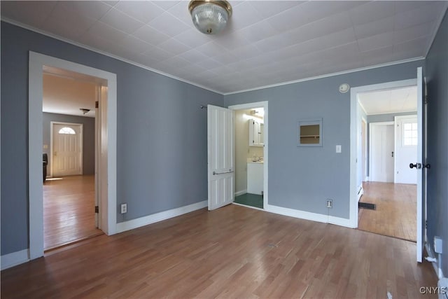 unfurnished bedroom with crown molding, baseboards, visible vents, and wood finished floors