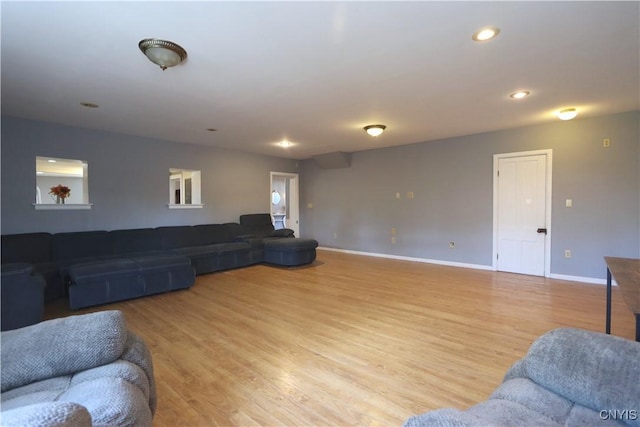 living area with baseboards, recessed lighting, and light wood-style flooring
