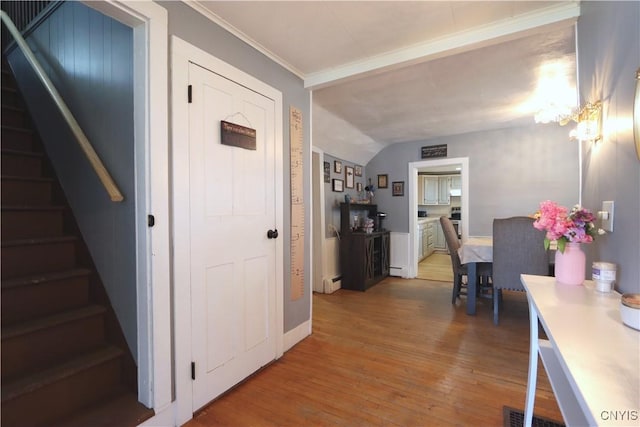 hall with baseboard heating, vaulted ceiling, a chandelier, light wood-style floors, and stairs