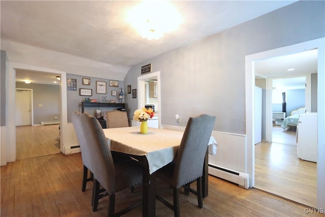 dining area with light wood finished floors and a baseboard heating unit