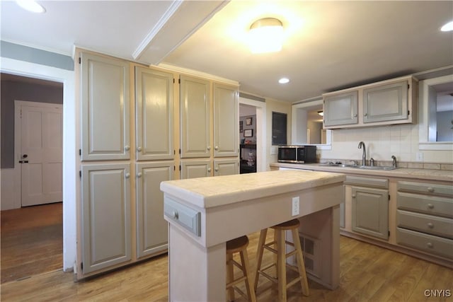 kitchen with a center island, light wood-type flooring, a sink, stainless steel microwave, and recessed lighting