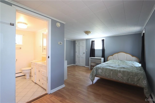 bedroom with multiple windows, baseboard heating, light wood-style floors, ensuite bathroom, and ornamental molding