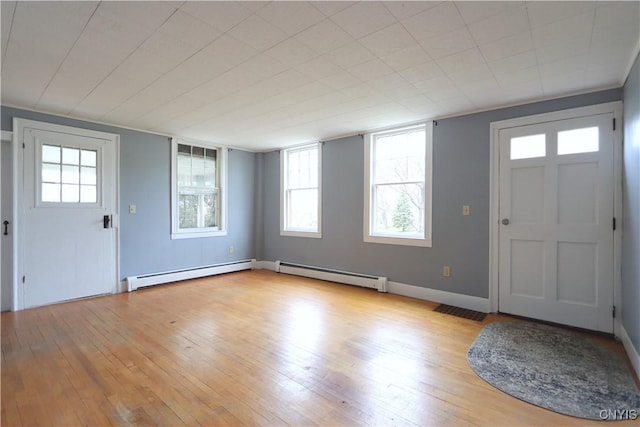 entrance foyer featuring wood-type flooring, a healthy amount of sunlight, and baseboard heating