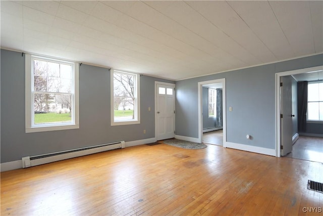 interior space featuring light wood-style floors, visible vents, baseboards, and a baseboard radiator